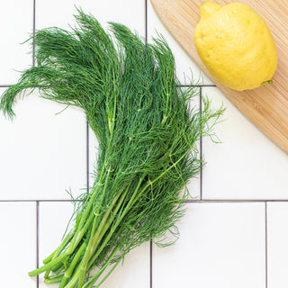 dill on a tile background with a cutting board and a lemon