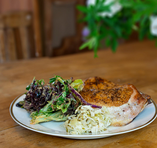 a plate with chicken leg quarter and salad and cabbage