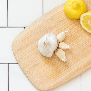 garlic cloves on a cutting board with lemon garnish