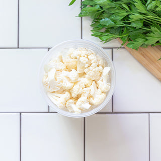 Sliced Raw Cauliflower in a reusable bowl on a tile background