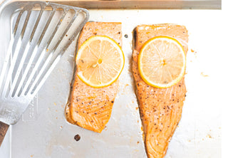 Two fillets of Salmon on a pan topped with lemon