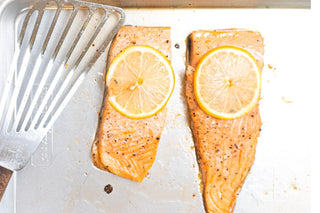 Two fillets of Salmon on a pan topped with lemon