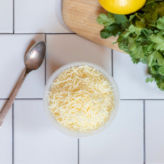 shredded parmesan in reusable container on a tile background 