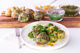 meatballs and potatoes with green olive chimichurri on a white plate