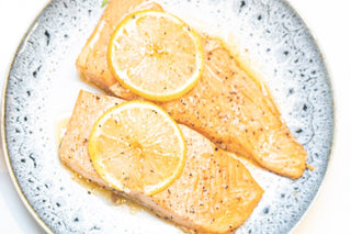 two fillets of salmon on a plate topped with lemon